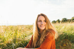 A woman sits outside smiling because she is grateful for Soledad House's relapse prevention support helping her manage relapse triggers